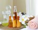 Spa accessories wellness setting with cosmetic bottles and salt with white plumeria flower, blurred massage stones in wooden bowl in background, spa concept, copy space