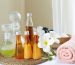 Spa accessories wellness setting with cosmetic bottles and salt with white plumeria flower, blurred massage stones in wooden bowl in background, spa concept, copy space